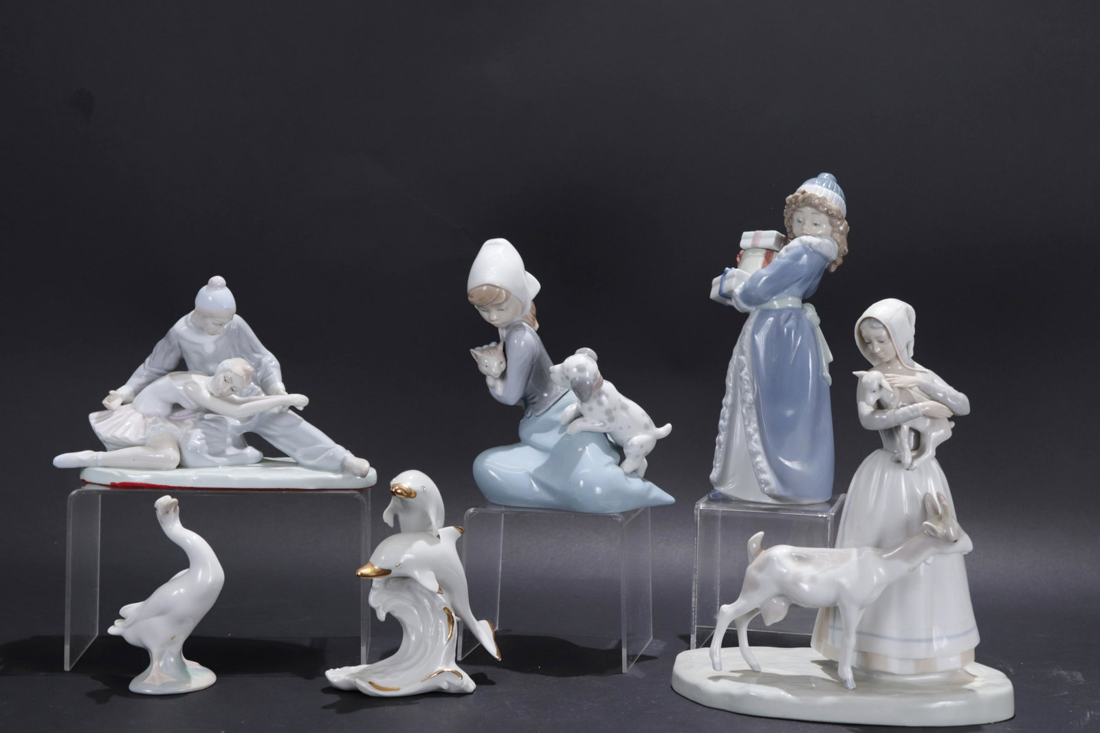Lladro and Additions Porcelain Figurines: Four marked Lladro. One possibly Lladro no obvious mark. An addition marked Capodimonte (Italy) dolphins. A Lladro box included. Dimensions: Goose 4.5"H tallest 9.5 (RPSA166/6)(JP)