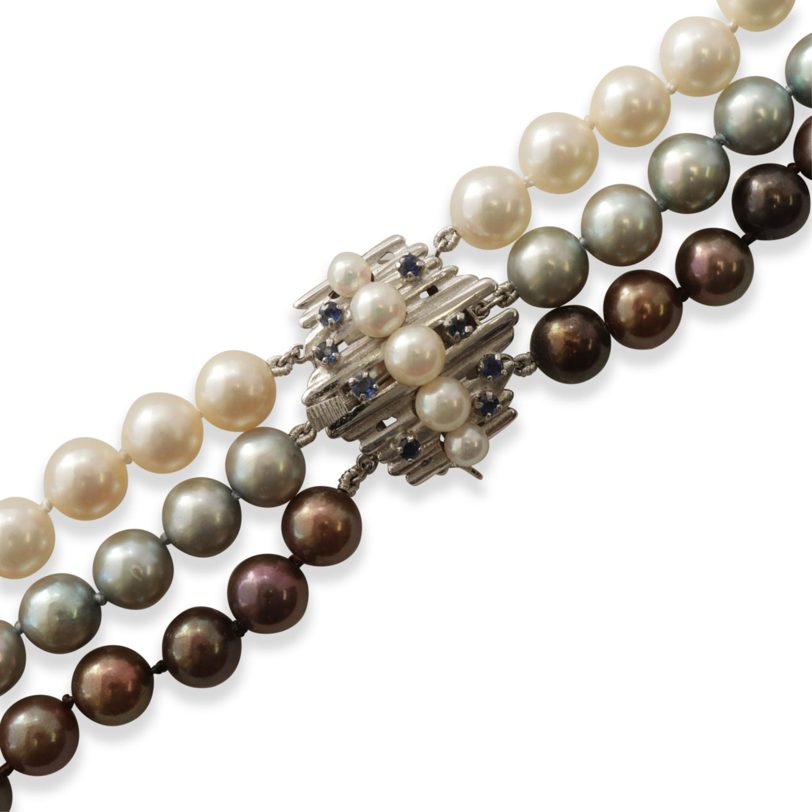 Tahitian, Blue, and White Pearl Necklace: A triple strand pearl necklace with Tahitian, blue, and white natural pearls. Each of about 7.85 mm diameter. 30" long. 14k white gold clasp with five white pearls and 8 sapphires. Property from the c