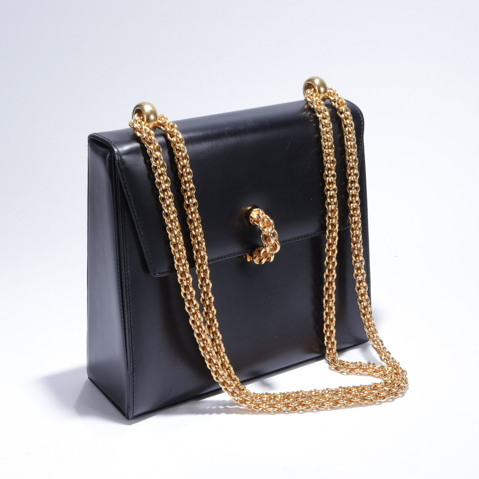 Vintage Paloma Picasso Shoulder Bag: A vintage black smooth leather shoulder bag by Paloma Picasso, made in Italy. Chunky gold tone chain handle with chain motif closure. One interior zip pocket. Circa 1990s. 7.5" x 8.25" x 2.75", 20" sh