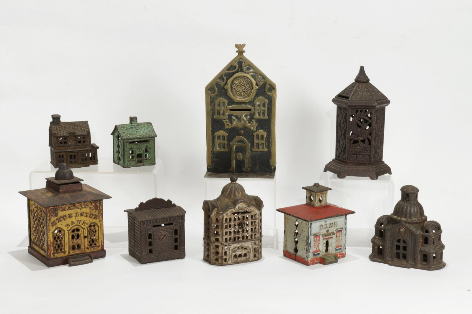 19th-20th C.Cast Iron Banks - Cottage: 9 Cast Iron Banks and Houses, includes Hall's Excelsior Mechanical Bank, yellow version with original polychrome painted decoration and wooden pop-up monkey cashier figure, marked "PAT DEC 21 1869" at