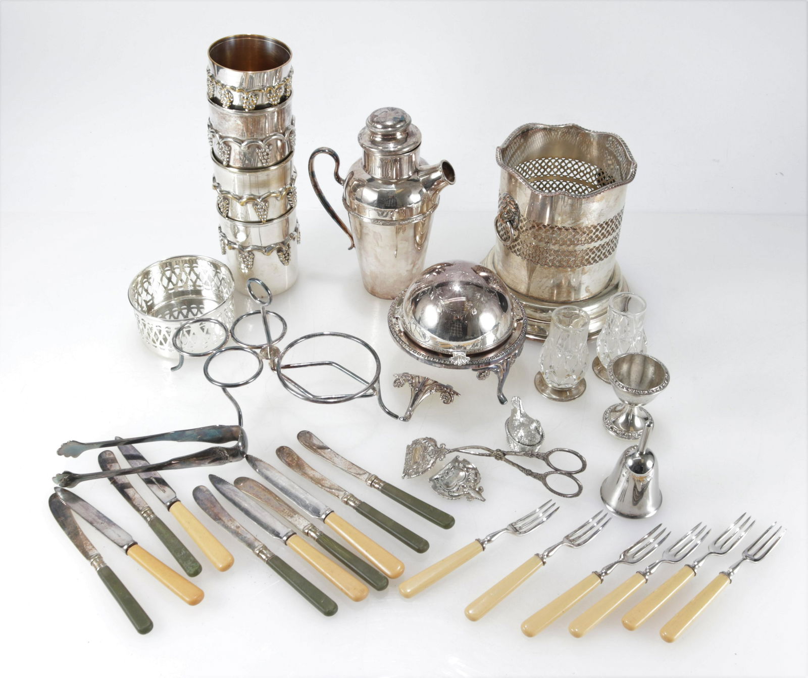 Silverplate Tabletop Barware Items: Wine Caddy, Pr. of cut crystal bud vases, grape ornamented cups, wine coaster, cup, bell, hen, cocktail shaker, Mappin and Webb flatware, circular domed caviar dish, tong,condiment holderDimensions: V