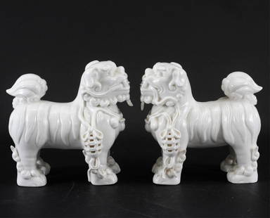 Pair of Standing Porcelain Fu Dogs: Pair of Unique Standing Porcelain Fu Dogs, 20th C. Mirrored pair of Dehua style porcelain Fu Dogs well-modeled, collar and bell with cord each mouth. 7.5" H Property from the Estate of Marian Galewitz