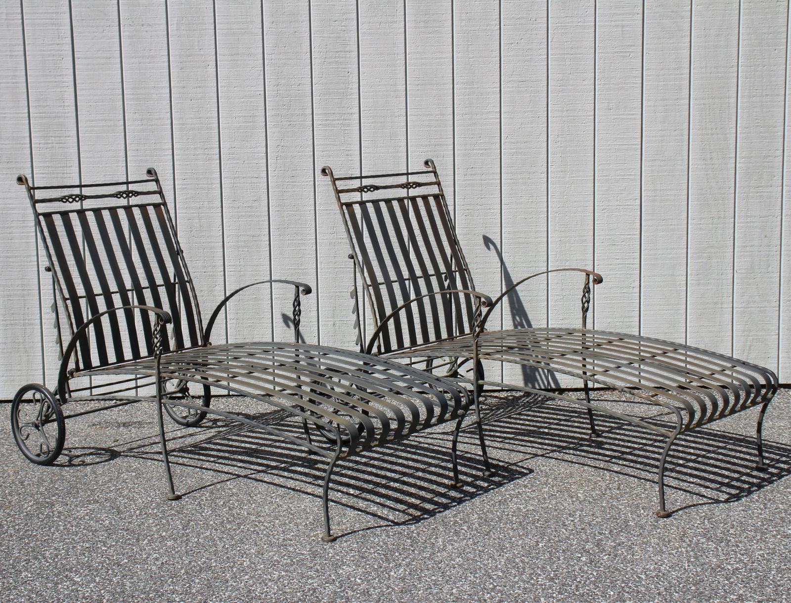 Pair Pool Patio Metal Chaise Lounges: Black metal painted chaises on wheels. 28" W X 64" L X "H Seat length; 50" min. to 81" laid flat. Property from a Fine Collection of Antiques & Decorative Art, Rumson, New Jersey.