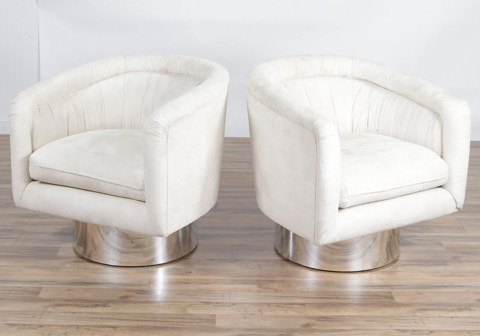 Pair of Karl Springer Style Swivel Club Chairs: Pair of Karl Springer Style Swivel Club Chairs, possibly Leon Rosen for Pale. Upholstered in odd white super suede. Dimensions: 29.5" H x 29.5" W x 29" D Property from the Estate of John 'Parker' Prin