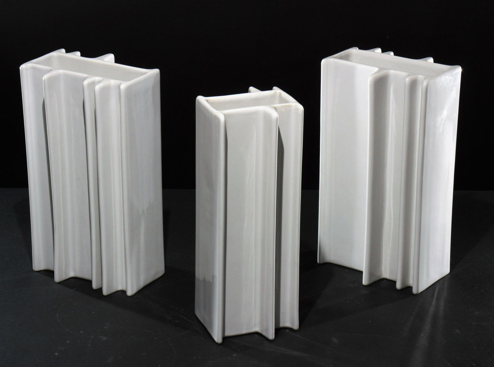 Angelo Mangiarotti - Three Vases: Angelo Mangiarotti for Fratelli Brambilla, Pair of white ceramic vases together with a third. Stamped on bottom. Dimensions: Pair 10" H x 5.75" x 4.5"Single 10.5" x 4" x 4" Property from the Estate of