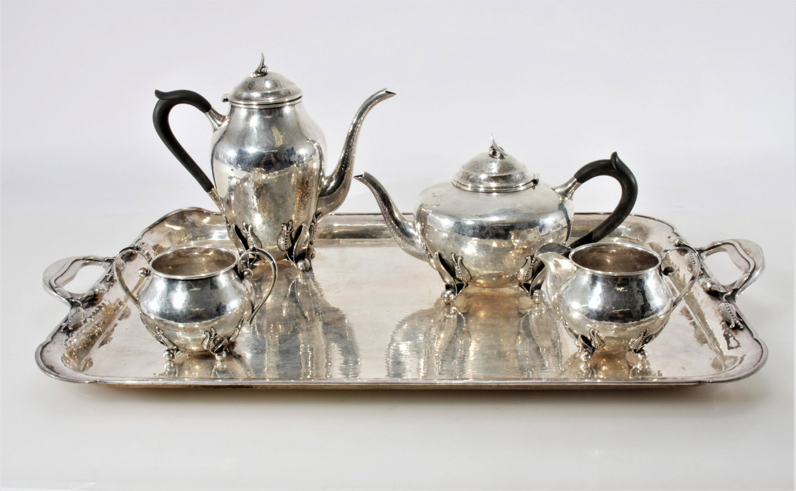 Carl Poul Petersen (1895-1977) Sterling Coffee Set: Four piece blossom or peapod design sterling service with coffee pot, tea/hot water pot, creamer, and sugar with marks Petersen, Hand Made Sterling and trade/hallmarks on bases. Pots with bone handles