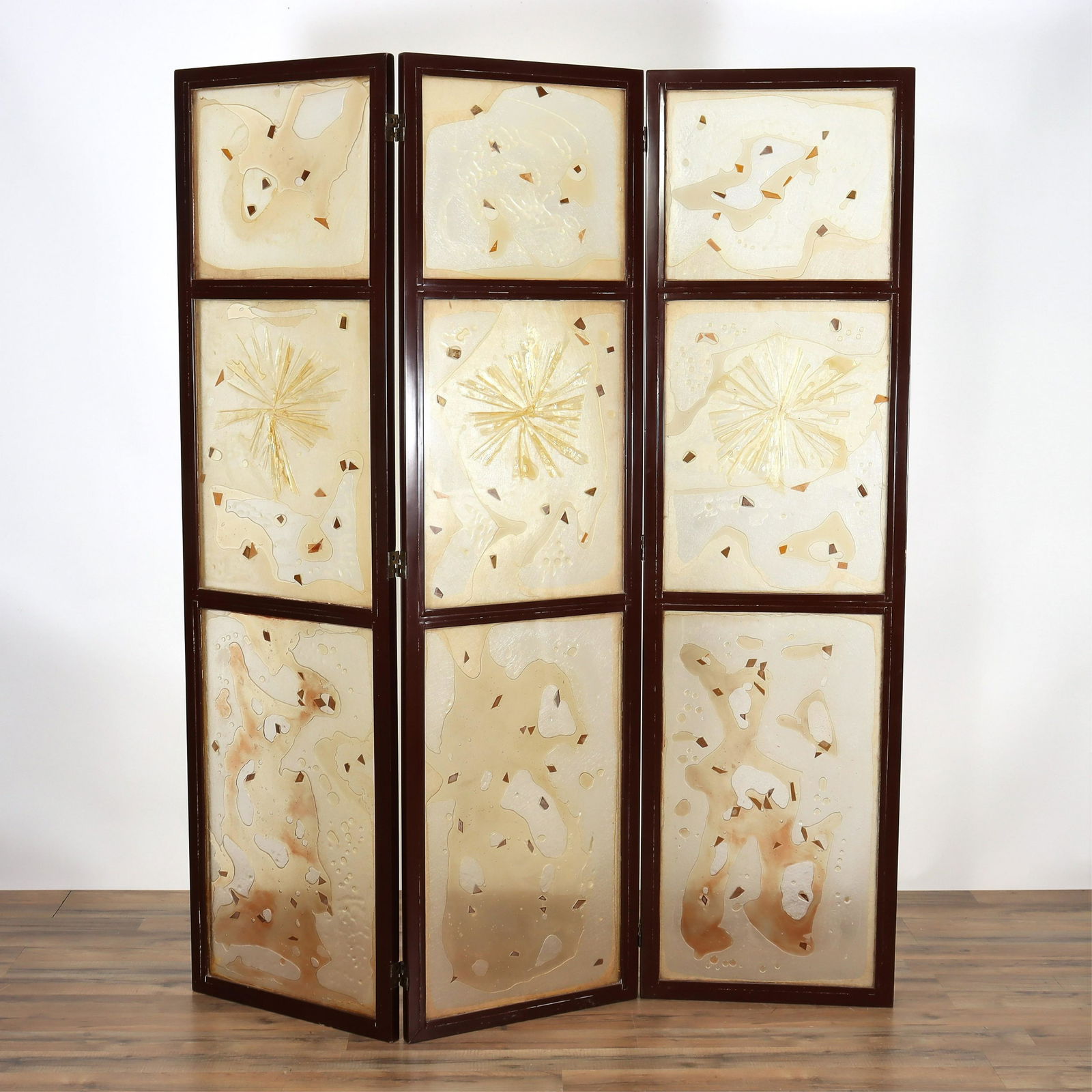 Style Of Zahara Schatz Three Panel Room Screen: Three hinged panels as room divider or screen. Inset acrylic panels with watery, globular forms and geometric "chips" in honey, tans, brown colors abstracted motif. Painted or lacquered wood frame in