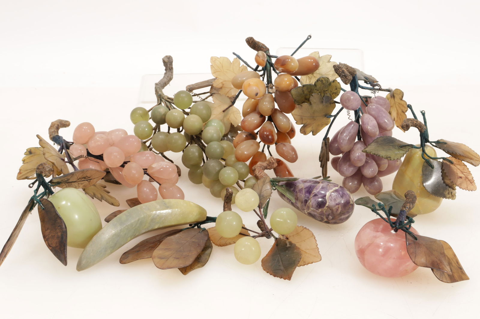Group of Hardstone Fruits: Group of Hardstone Fruits. Comprising rose quartz apple and grapes, amethyst grapes and pear, serpentine pear and banana, jadeite grapes, jasper grapes. Largest grape bunch 9" long.