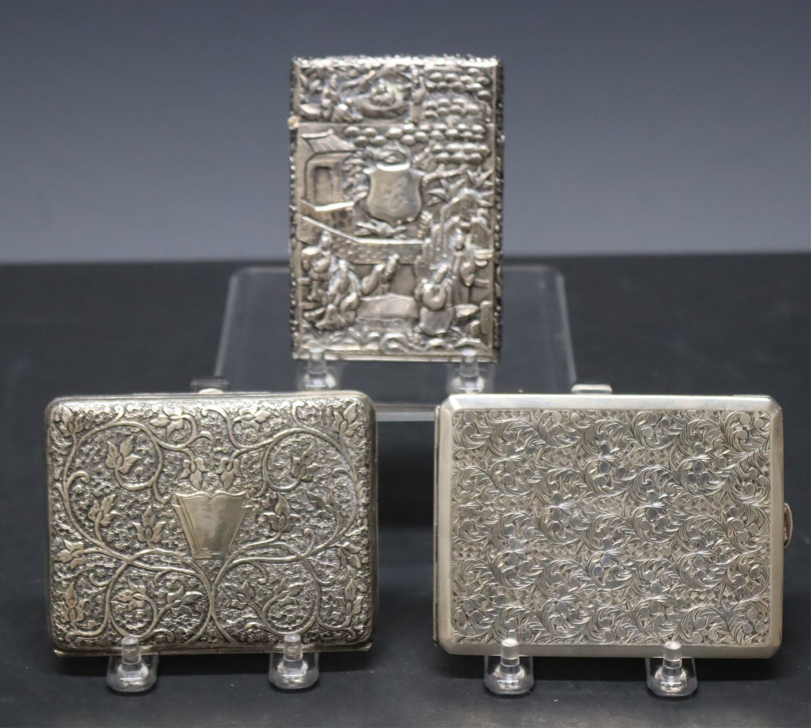 Three Sterling Silver Compacts: Three sterling silver compacts. Comprising: Asian motif repousse cigarette case depicting figures playing a board game under center shield with C monogram, bird and bamboo motif verso, vermeil interio