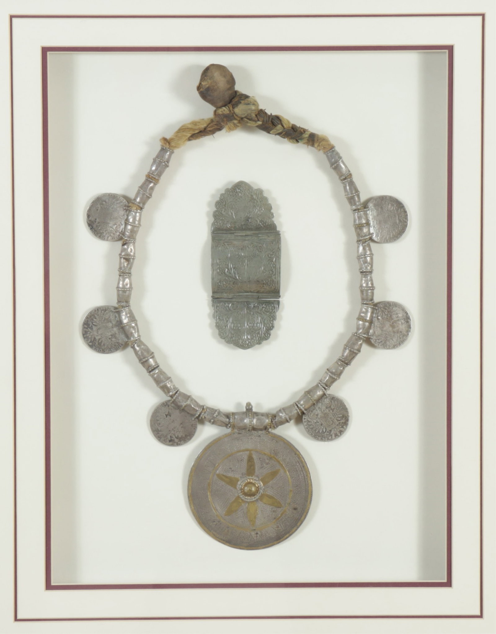 Omani Tribal Smot Framed Necklace & Bracelet: Omani Tribal Smot Necklace & Bracelet. Brass inlaid metal. Incorporating Austrian Maria Theresa Thalers coins, 1780. Framed 25.25" H x 20.75" W Property from the Estate of Aashish and Dinyar Devitre.