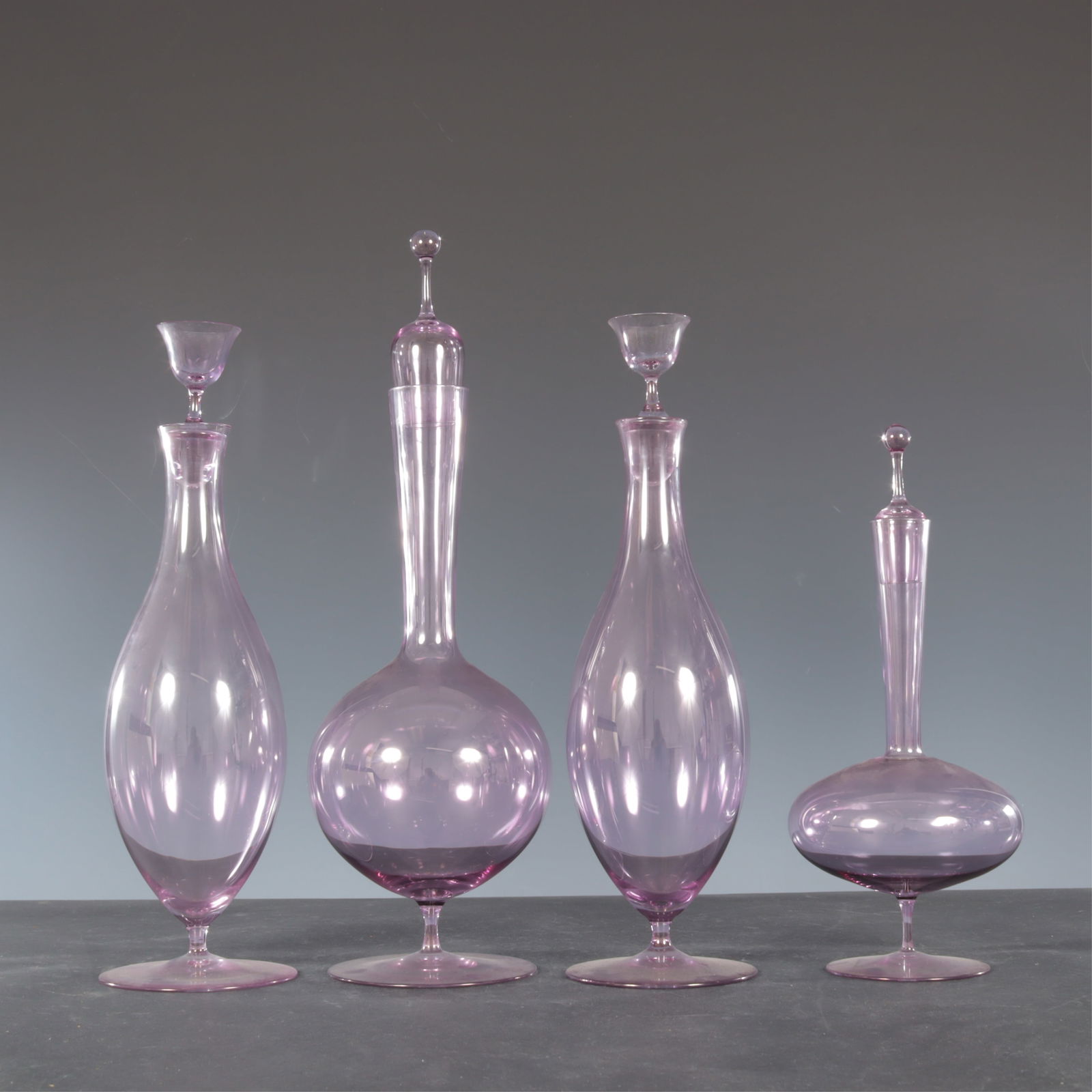 Four Oswald Haerdtl for Lobmeyr Decanters: A group of four Oswald Haerdtl for Lobmeyr lavender glass decanters with stoppers. Including a pair and two bulbous individuals. Unmarked.Tallest 12.5" H without stopper.