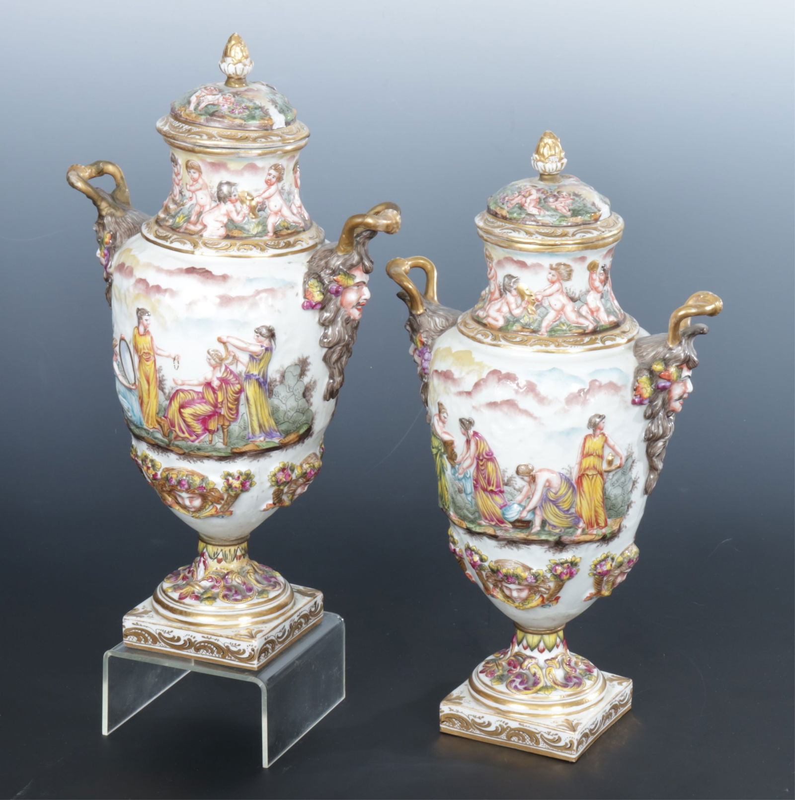 Pair 19th C. Capodimonte Lidded Urns: Pair of Capodimonte 19th C. Porcelain lidded urns, hand painted relief of classical Renaissance and Neoclassical scenes with gold painted handlesDimensions: 13 1/2 x 8Property from a Washington Connec