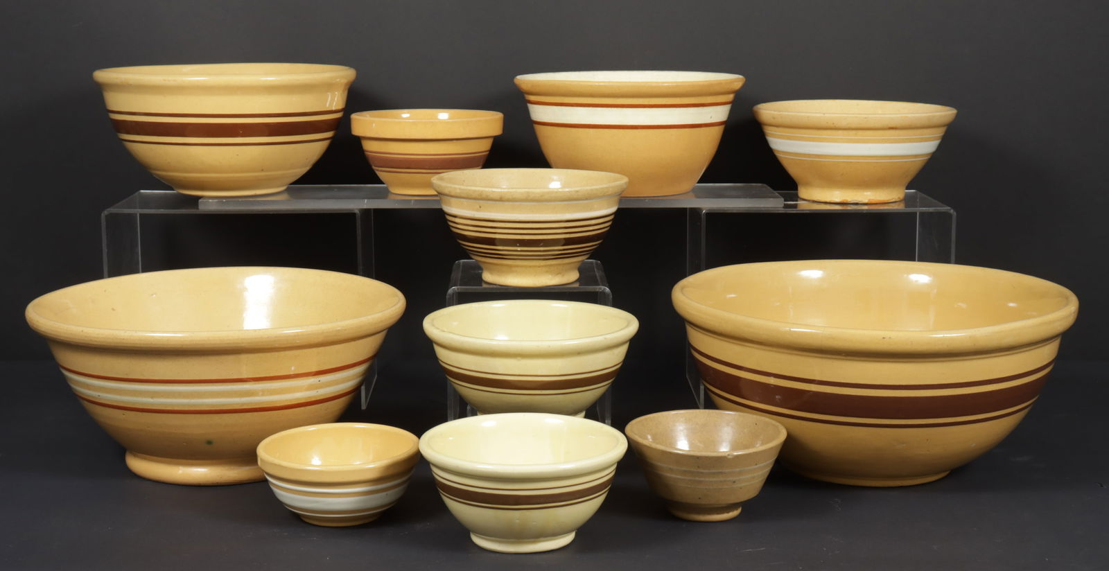 Assembled Nest of 11 Yellowware Bowls: Assembled nest of yellow-glazed earthenware bowls, with brown and white stripes.Dimensions: Smallest: 2 3/4" H x 5 1/4" Dia; largest: 6 1/4" H x 14" Dia