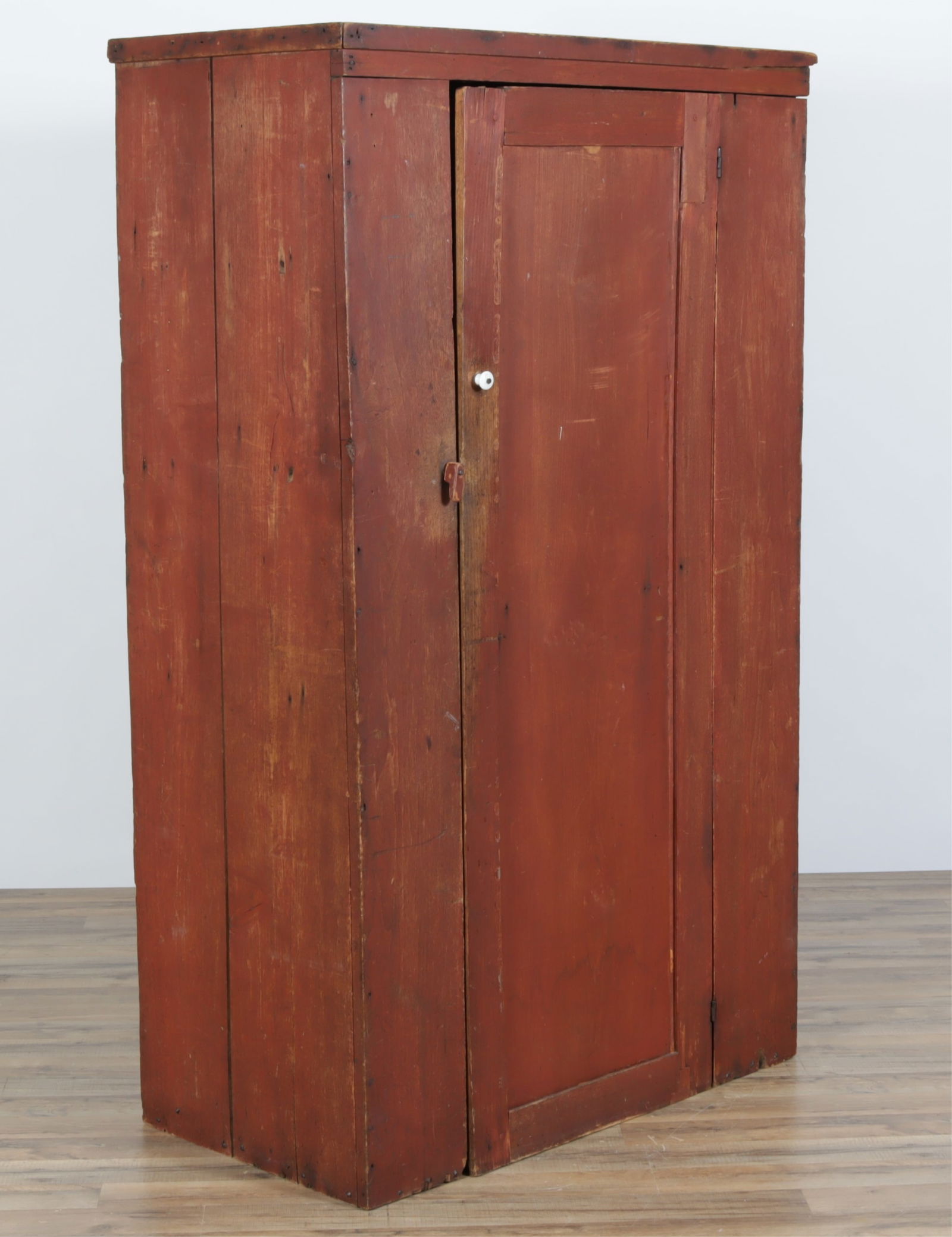 American Red Stained One Door Cupboard: American Red Stained One-Door Cupboard, 19th Century, one drop panel door opening to a shelved interior with ceramic pull and pivoting wood latch.Dimensions: 64 3/4 H x 38 1/4" W x 21" D