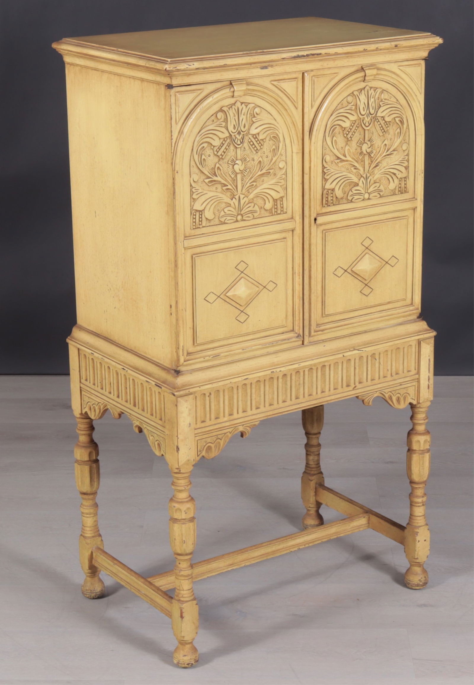 Yellow Painted Berkey & Gay Lift Top Cabinet: Yellow painted Renaissance Revival style cabinet on stand, made by Berkey & Gay, Grand Rapids, Michigan, 20th Century, with hinged lift-top labeled underneath, cabinet with two relief-carved doors