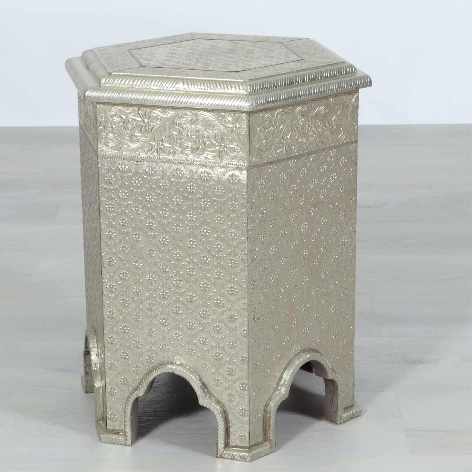 Orientalist Repousse Metal Clad Hexagonal Table: Orientalist style repousse metal (tin?) clad hexagonal low table, 20th Century, with molded top, arched base, stylized foliate decoration.Dimensions: 20 1/2" H x 17 3/4" W x 15 1/2" DProperty from