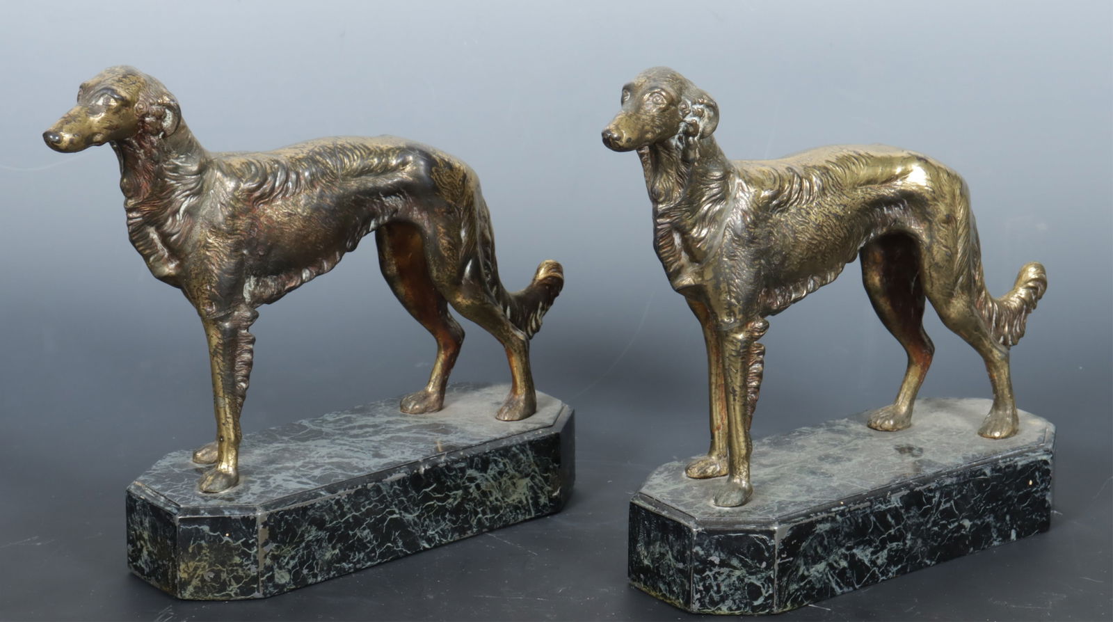 Pair of Metal Whippet Book Ends: A pair of brass plated cast metal book ends in the form of Whippets or Greyhounds, on a faux painted marble base. Dimensions: 8" H x 7.5" W x 2.75" D 