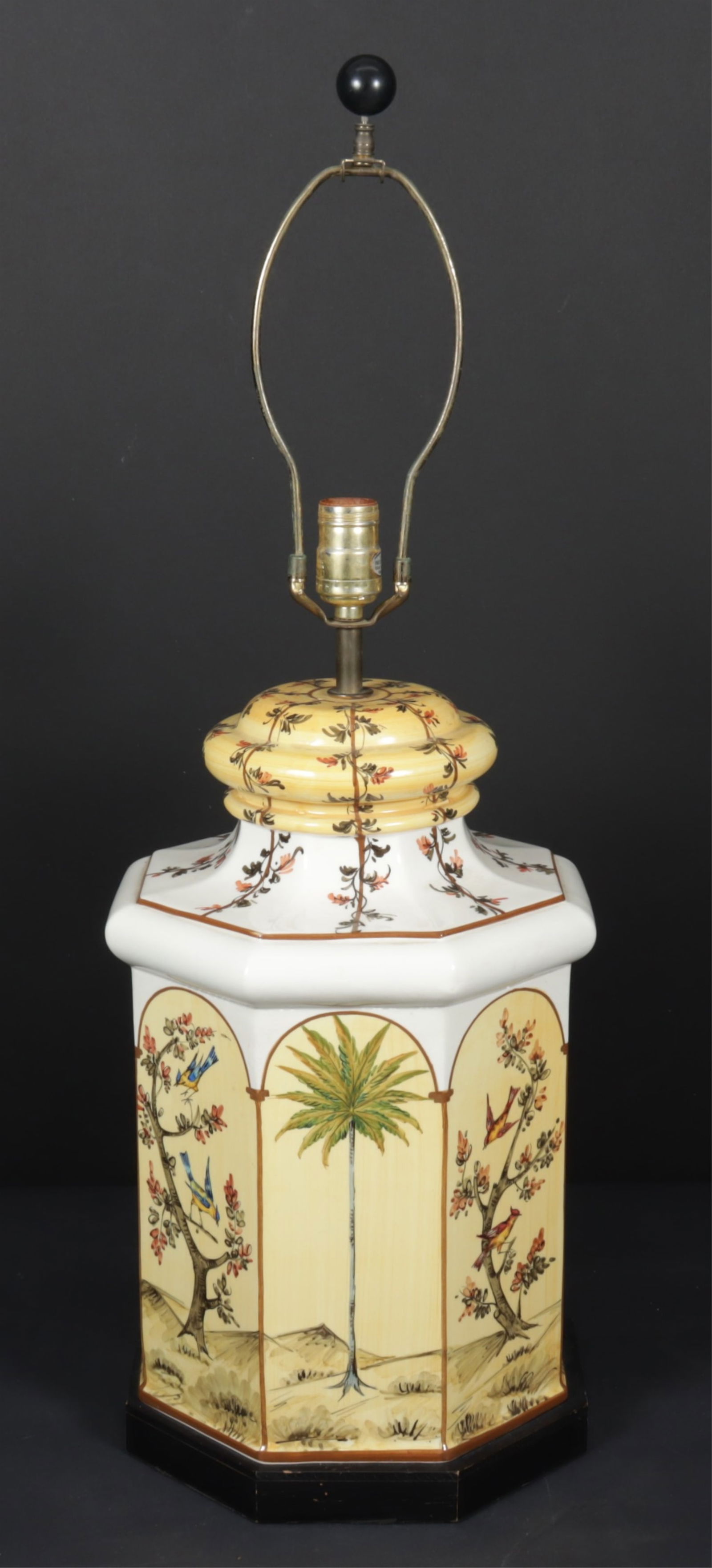 Vintage Tea Canister Ceramic Table Lamp: Vintage tea canister form ceramic table lamp with hand-painted floral sprays, arched views of palm trees and flowered trees with birds, set on a black octagonal wooden base. Dimensions: To the finial