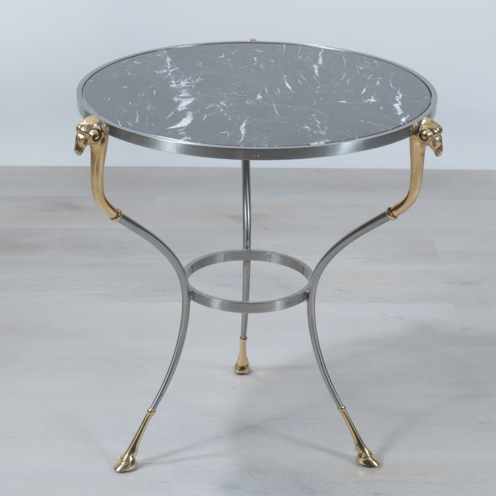 Maison Jansen Style Brass & Steel Gueridon: Maison Jansen Style Brass & Steel Gueridon. Brass Ram head supports, brass hoof feet, with black and white speckled marble top. Dimensions: 27.5" H x 24" Dia. 