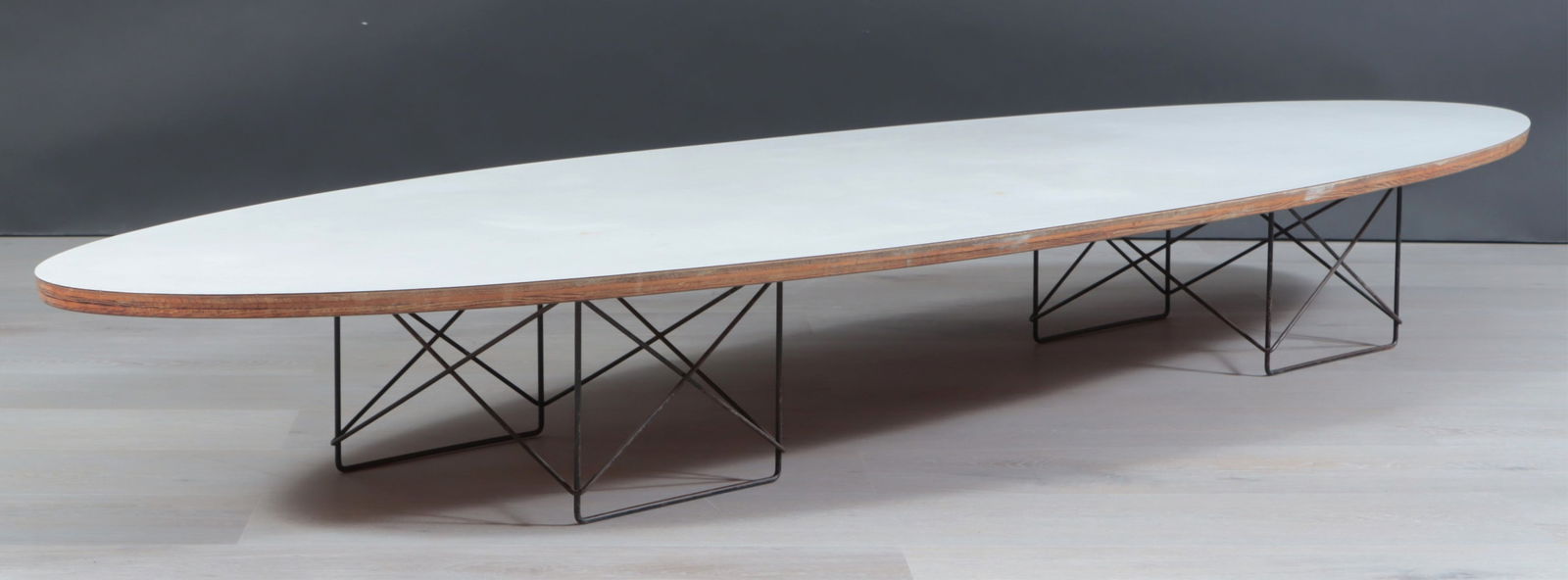Eames Herman Miller Surfboard Coffee Table: Eames for Herman Miller "Surfboard" coffee table, with a white laminate top, ebonized wire legs, underside stamped "3-22 BW." Dimensions: 10 /4" H x 88 3/4" W x 29" D 