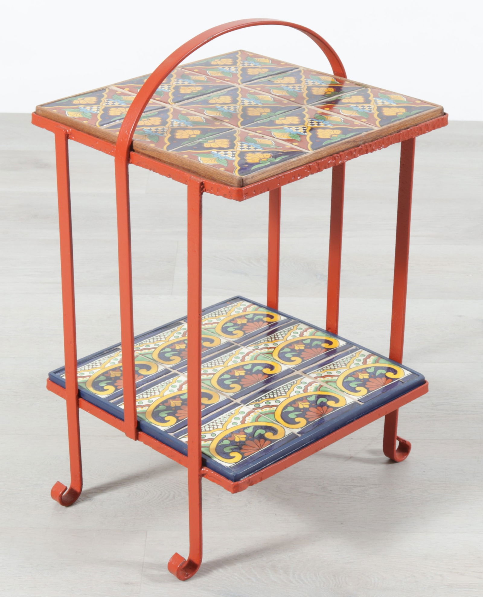 Mexican Talavera Style Pottery & Iron Table: Vintage two-tier Mexican Talavera style side table. Red painted iron frame with tile shelves, curved feet. Dimensions: 23.5" H x 14" W x 15.5" D 