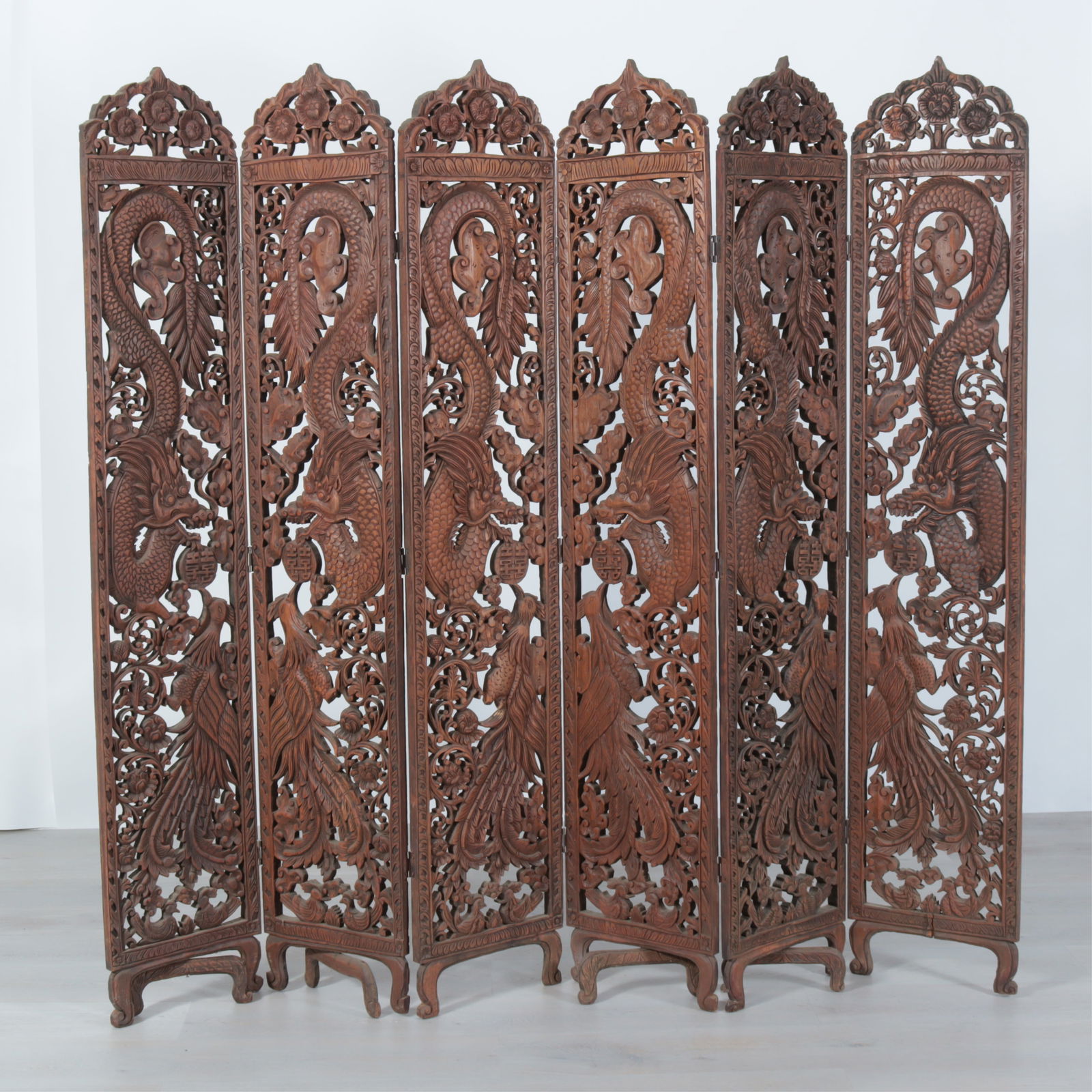 Southeast Asian 6-Fold Carved Screen: Southeast Asian carved teakwood 6-fold screen, probably 19th Century, depicting dragons and phoenixes, each panel with arched crest and short scrolled legs. Dimensions: Each panel 72" H x 14" W;