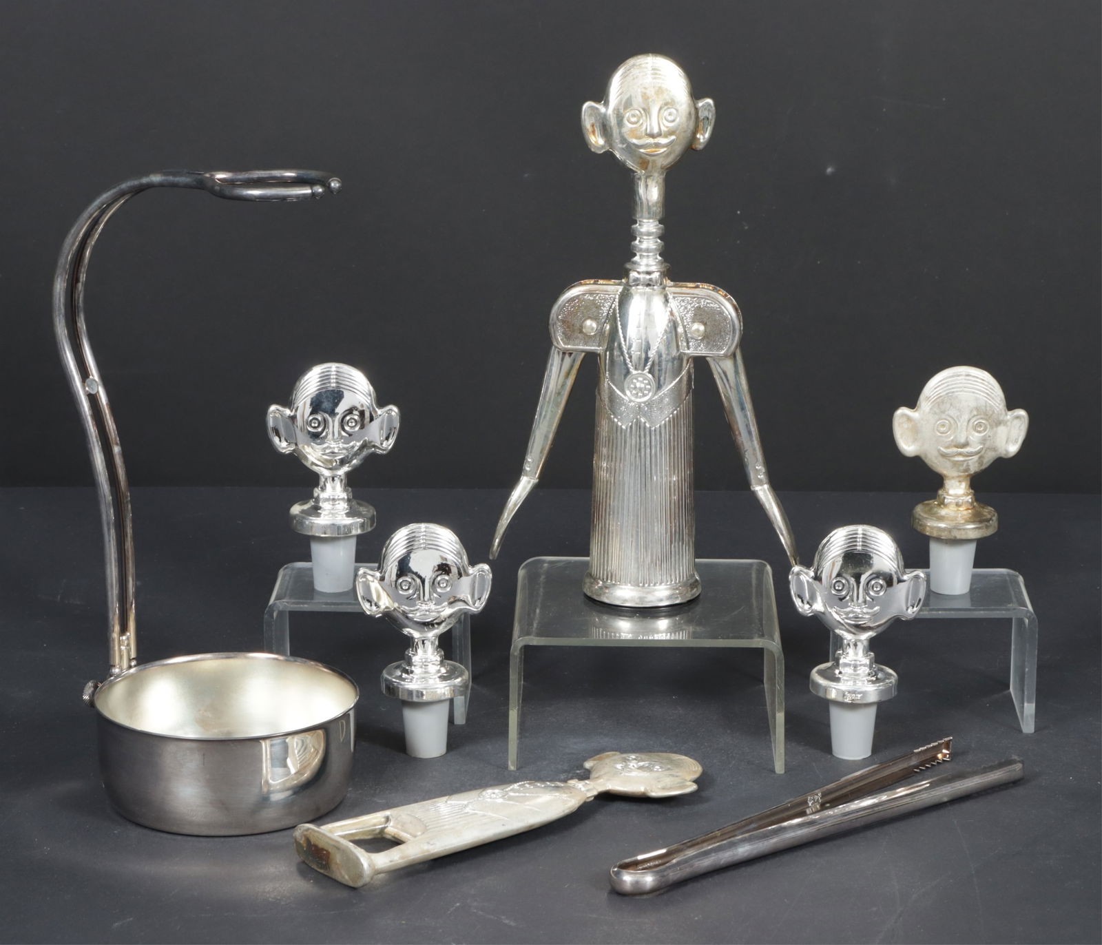 Pierre the Sommelier Silverplate Barware: A grouping of vintage Italian silverplate barware. Comprising: Pierre the Sommelier wine bottle opener, bottle opener, and four bottle stoppers. Together with a PM Italy silverplate wine bottle