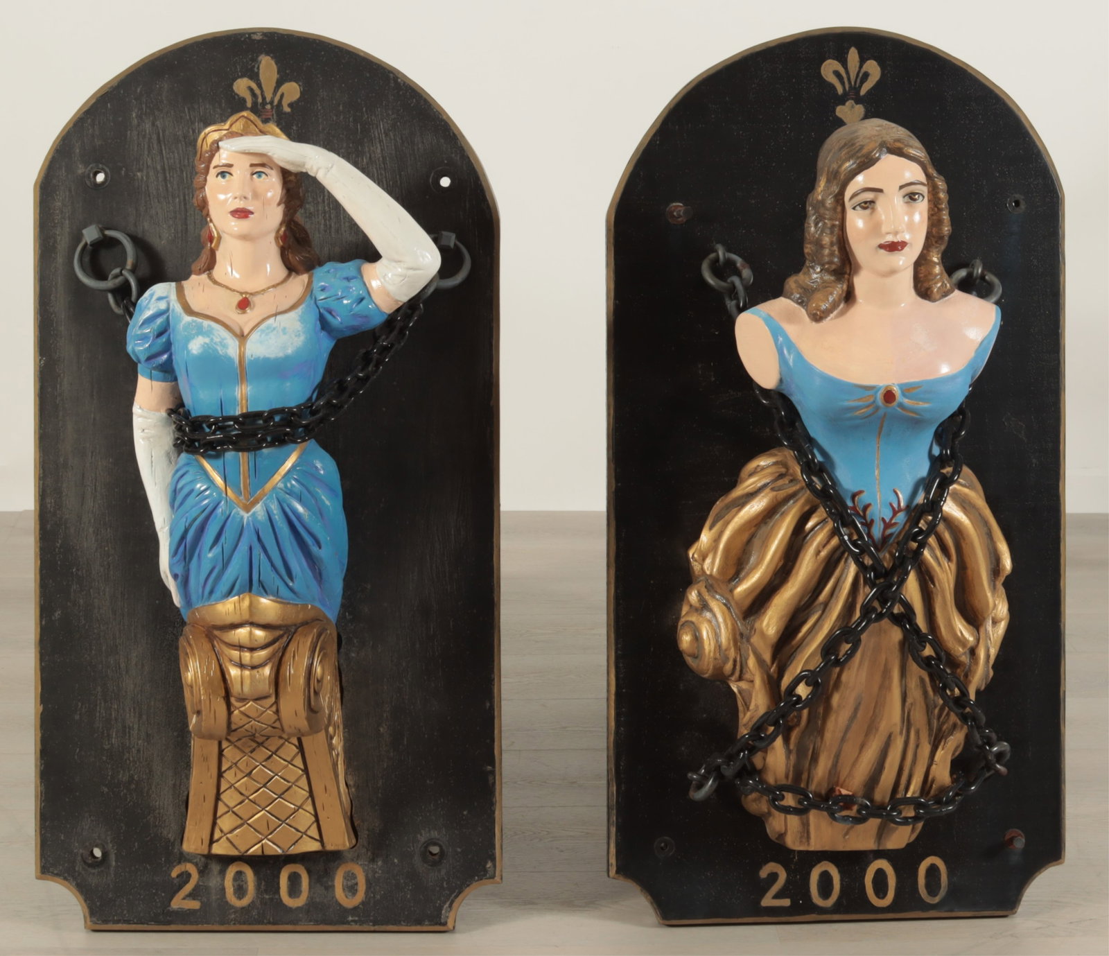 Two Maritime Ship Figureheads - painted wood: Two maritime ship figureheads, wood carved and painted, mounted onto board, 20th C., each with gold fluer de lis painted along the center of the top Dimensions: 41.75 H x 21.5 W x 14 D Collection from
