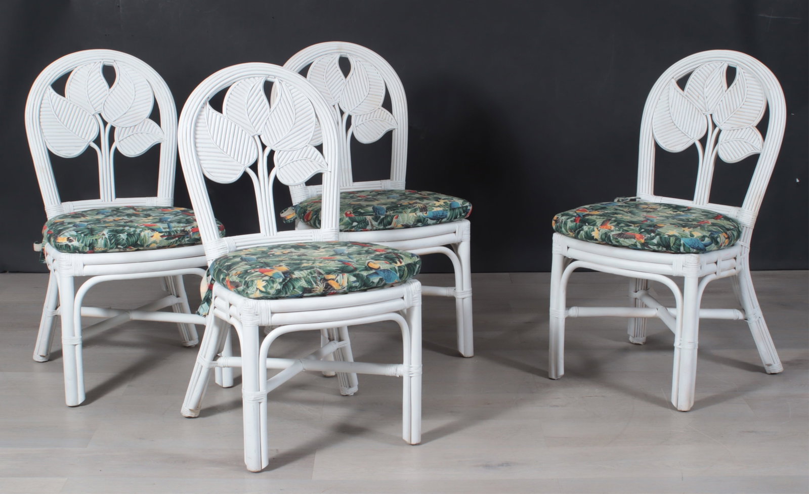 McGuire Style Grey Painted Bamboo Chairs: 4 McGuire Style White Painted Bamboo Chairs, upholstered in parrot print fabric. Removable seat pads. Dimensions: 38" H x 19" W x 28" D