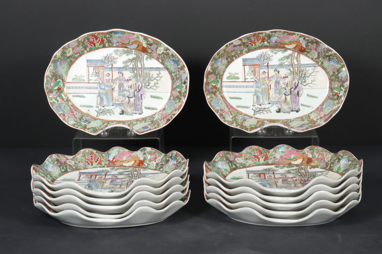12 Chinese Export Famille Rose Platters: 12 Chinese Export Famille Rose Platters with scalloped edge. Depicting figures in a garden.