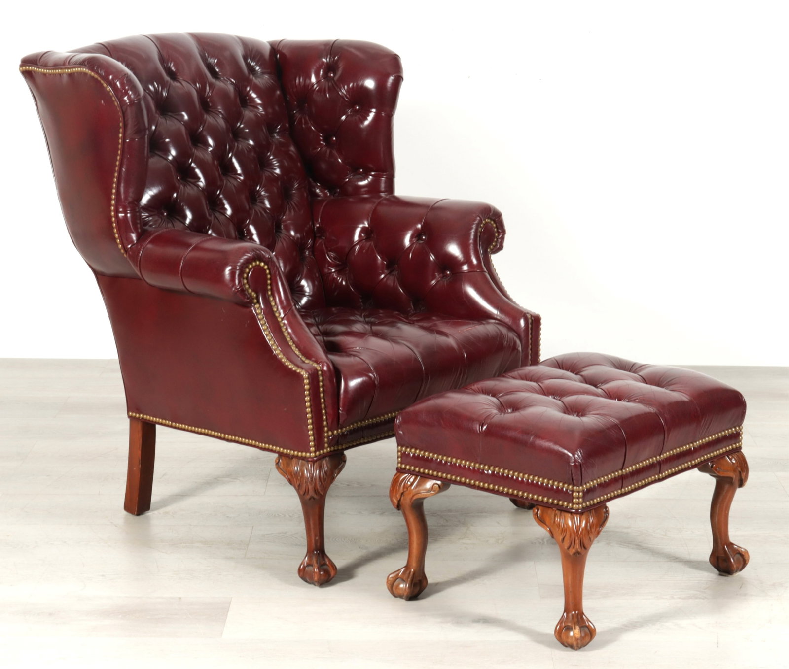 Leathercraft Chippendale Style Wing Chair & Otto: Leathercraft Chippendale style burgundy tufted leather wing chair and ottoman, nailhead trim, carved wooden claw and ball feet.