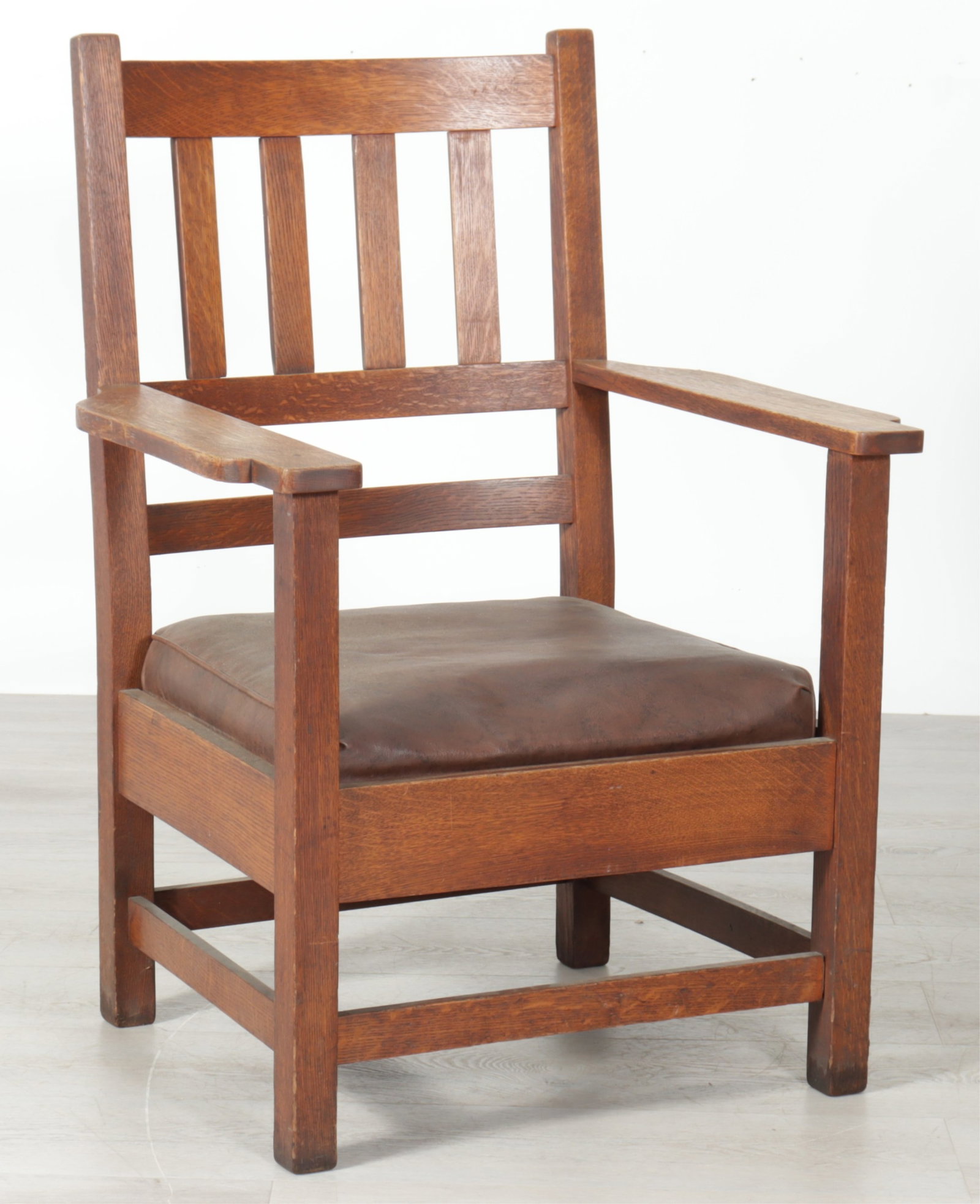 Arts & Crafts Oak Armchair: Arts & Crafts stained oak armchair, slatted back, brown leather covered cushion.
