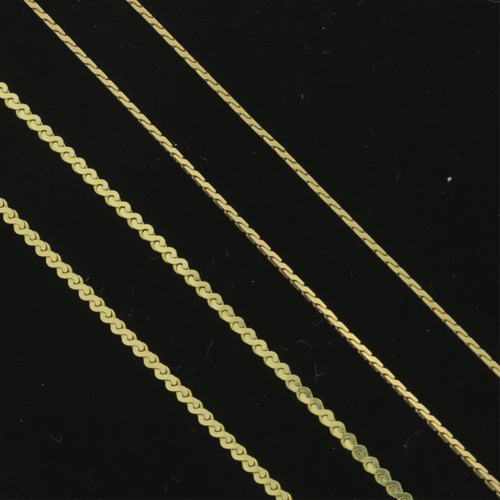 Two Italian 14K Dainty Gold Chains: Two vintage 14 karat yellow gold dainty chains. Comprising: 15" flat serpentine link chain together with a 16.5" modified serpentine or s-link chain. Weighing 3.4 grams. 15" and 16.5" long Property fr