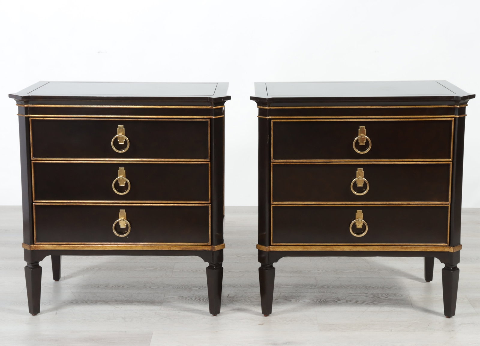 Pair of Marge Carson Ionia Commodes: Pair Marge Carson Ionia Commodes, ebony stained with gilded details, inset black granite top. 33.25" H x 32" W x 20.5" D