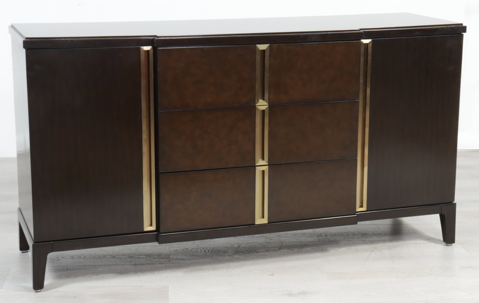 Marge Carson Lake Shore Drive Commode: Marge Carson Lake Shore Drive Commode. Dark walnut finish with brushed gold detail. Three drawers flanked by two doors enclosing two shelves. 36" H x 68" W x 19" D