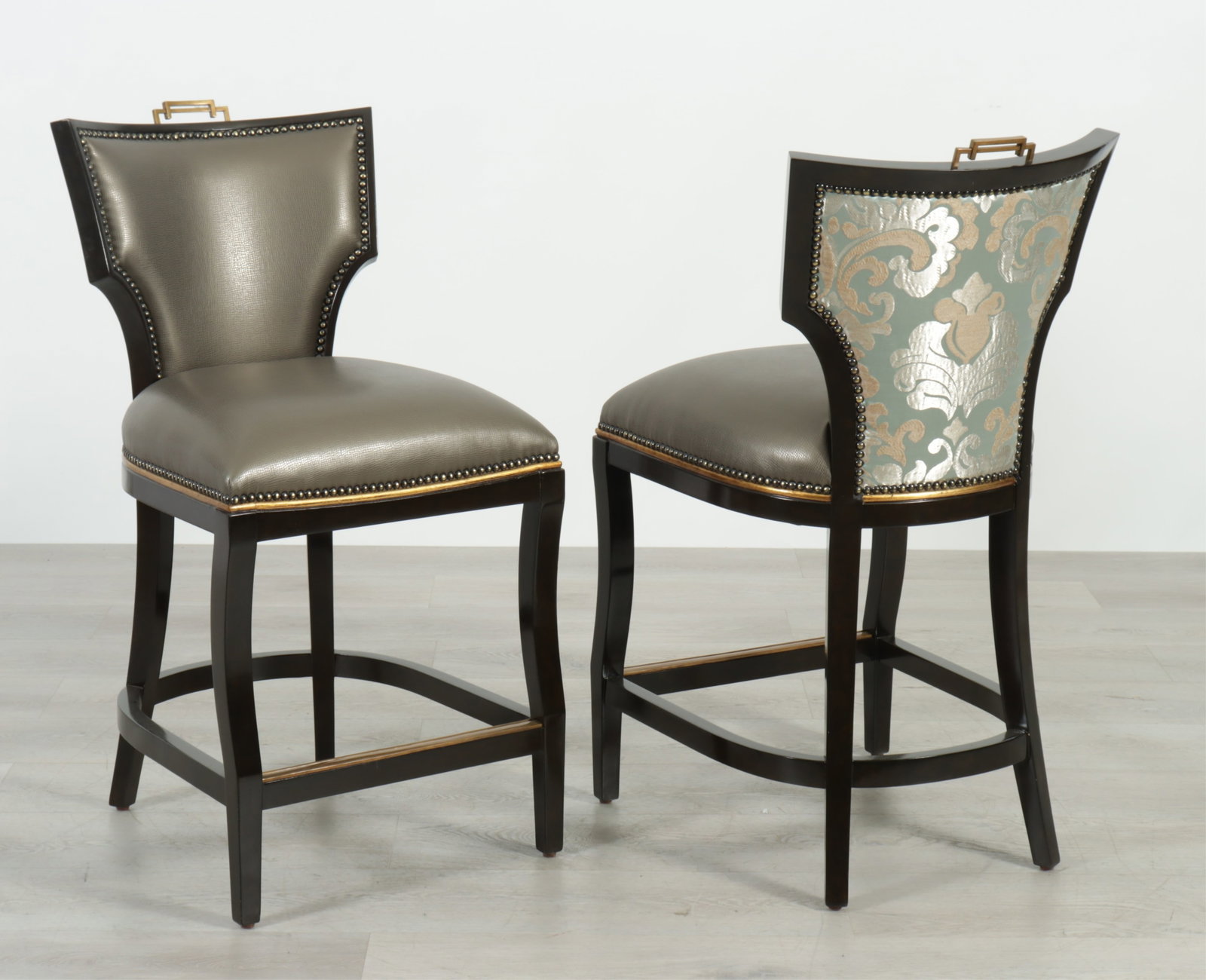 Pair Marge Carson Bolero Counter Stools: Pair Marge Carson Bolero counter stools, walnut frames with gilded details, brass handle and foot rail, in textured grey leatherette upholstery with complementary blue damask on back. 38.75" H x