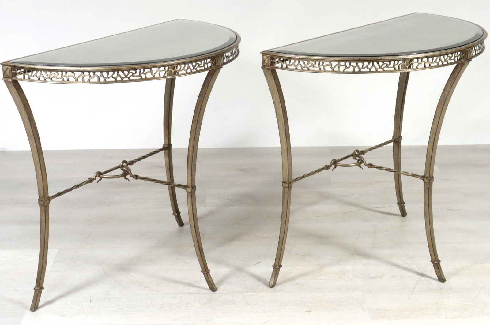 Pair Marge Carson Bolero Consoles: Pair of Marge Carson Bolero consoles, silvered metal frames with inset beveled mirrored top. 35.5" H x 39.5" W x 20.5" D