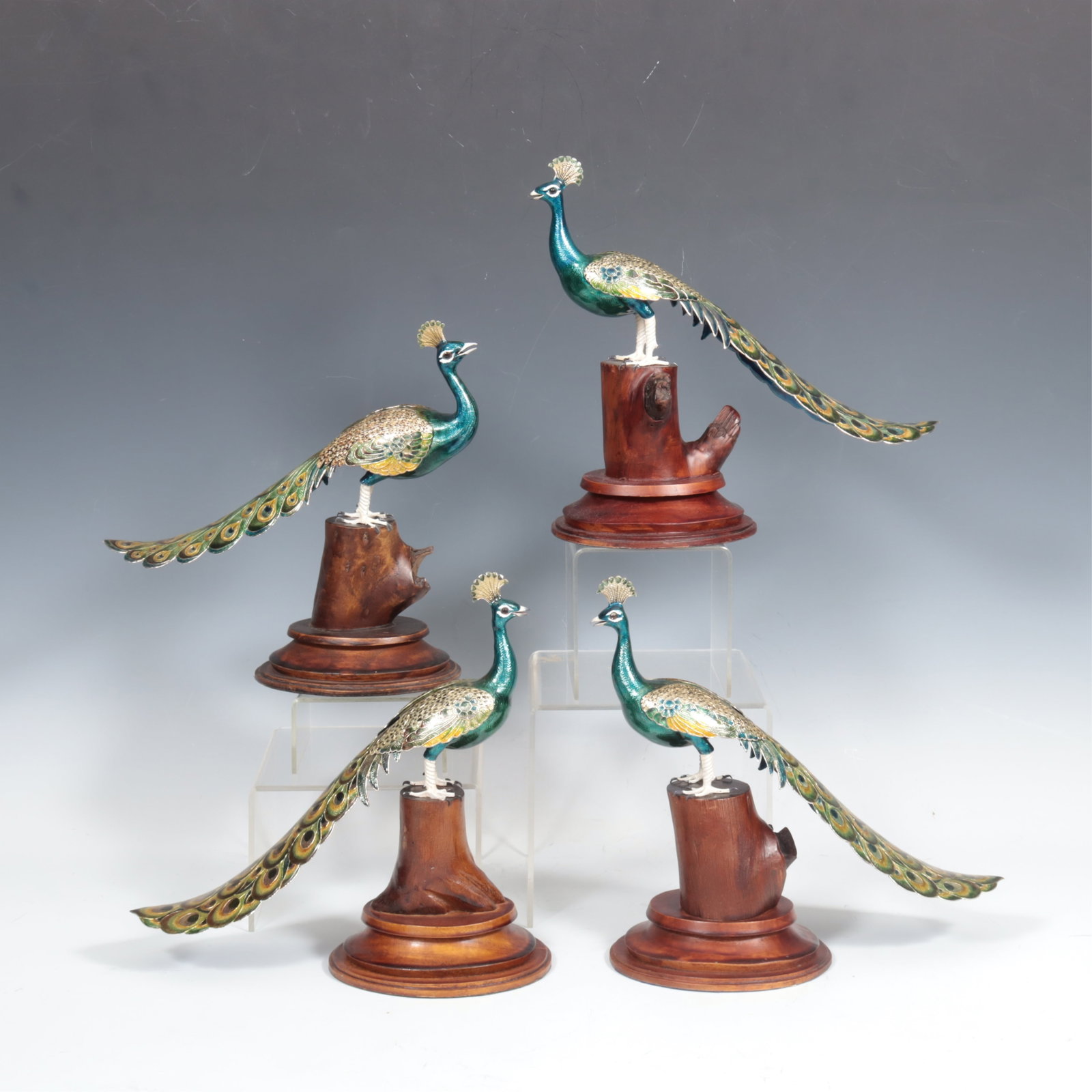 Four Indian Enameled Copper Peacocks: A group of four Indian enameled copper peacocks on wooden stands. 10" H