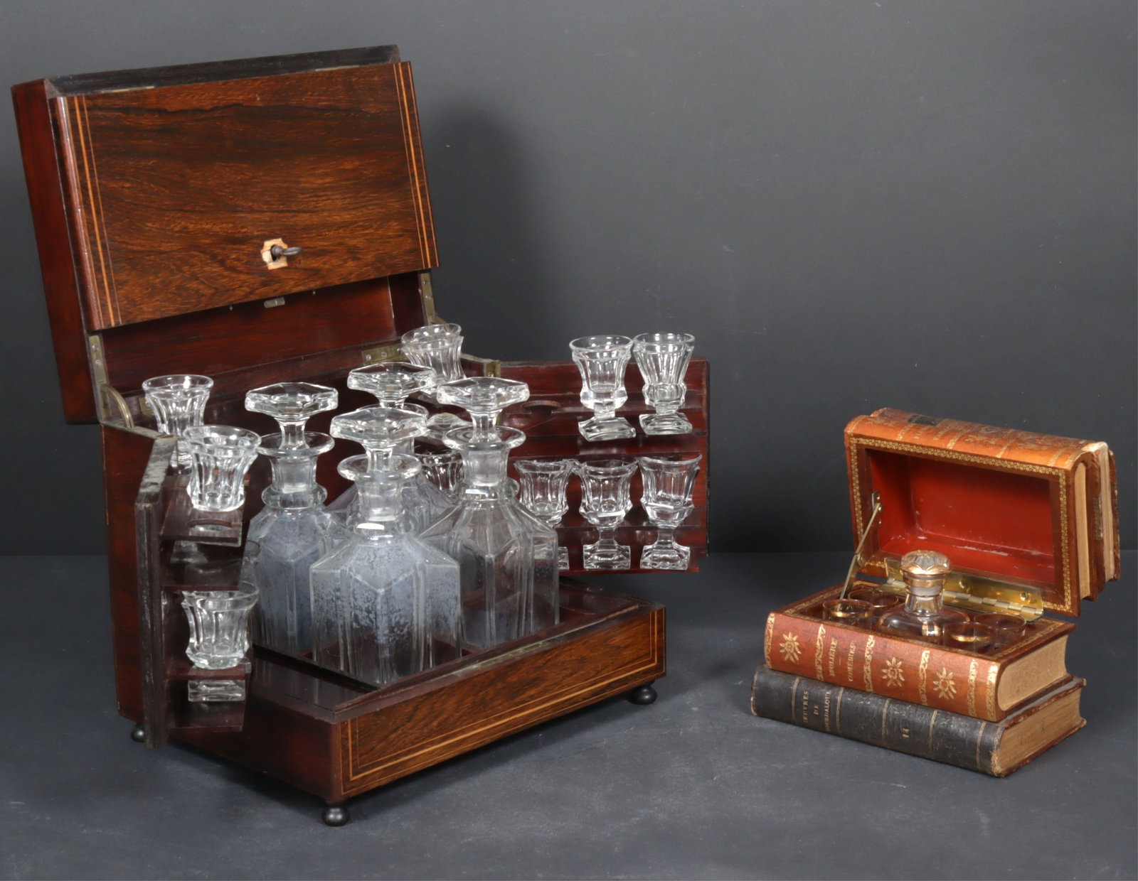 2 European Tantalus Liquor Boxes: Two European Tantalus Liquor Boxes, Late 19th C.- E. 20th C, includes a inlaid Rosewood lift top with bun foot and locking mechanism, along with a leather faux stacking book lift top case, marked