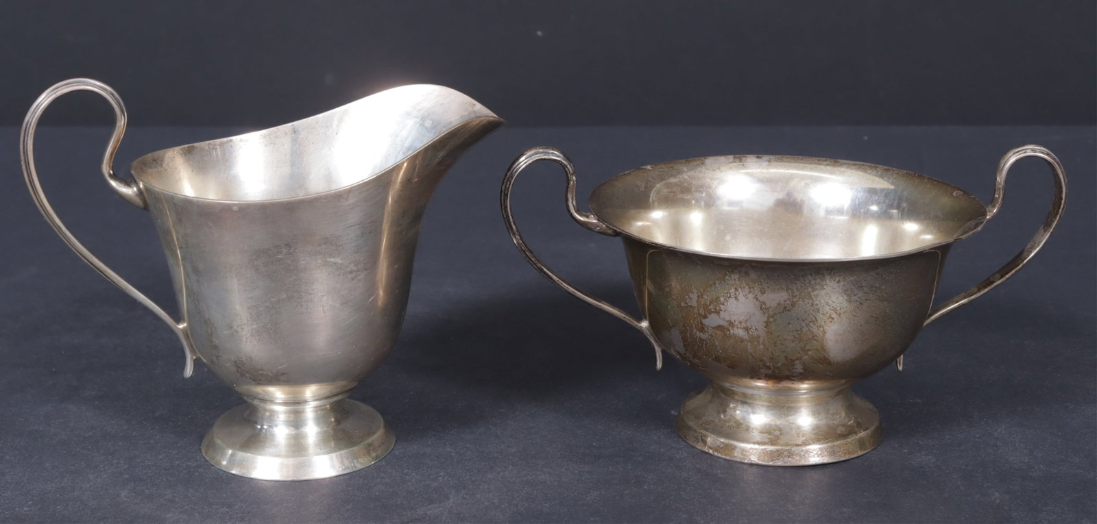 Worden-Munnis Co. Sterling Silver Cream and Sugar: Woden Munnis Co., Boston, MA, sterling silver cream jug and open sugar compote. Marked to bottom side. Weighing 10.79 OZT Creamer 4.25" H x 5" D x 3" W. Sugar 3.25" H x 6" W x 4.25" D