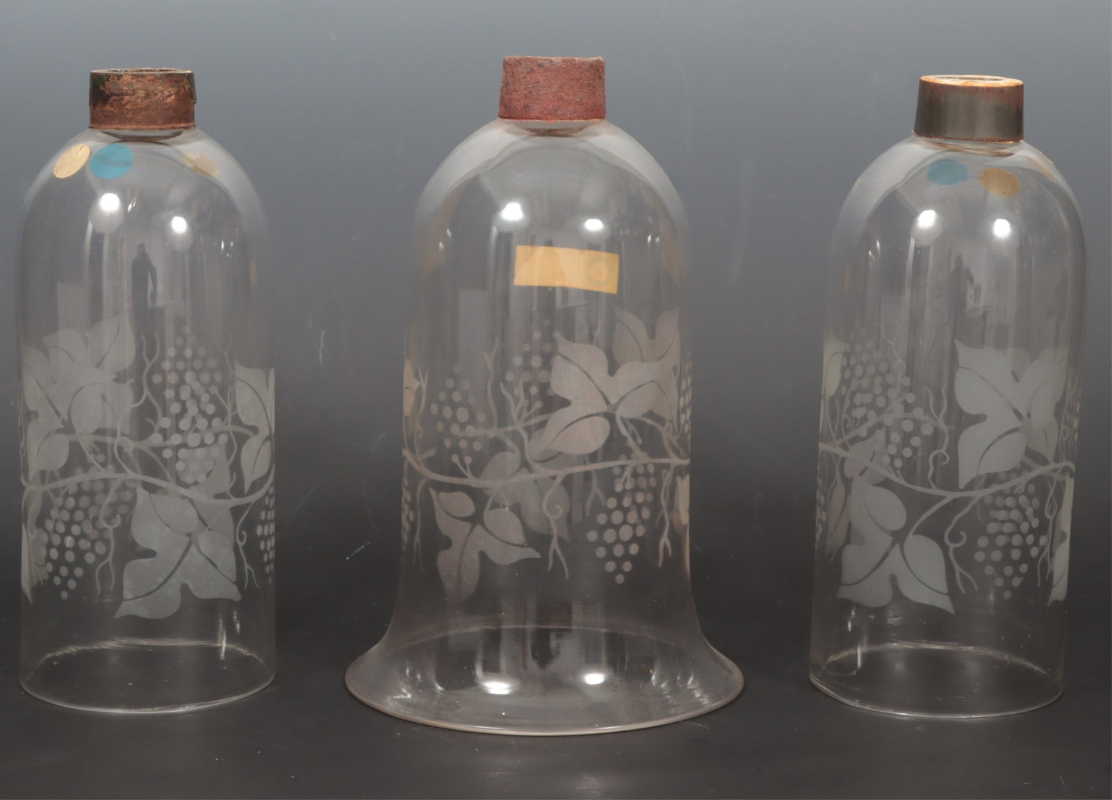 Three Antique Glass Hurricane Shades: A group of three antique etched glass hurricane shades comprising of a pair and a single with grape vine motif. Pair 10 5/8" H x 4 1/2" bottom diameter. Single 10 3/4" H x 6 7/8" bottom diameter.