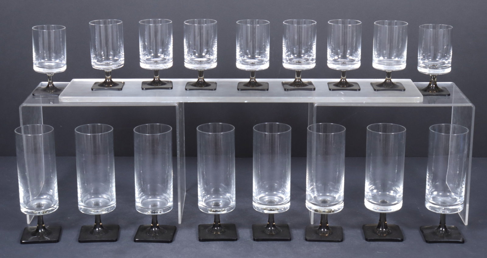 Berlin Linear Smoke by George Jensen for Rosenthal: Collection of 17 glasses, Berlin Linear pattern by George Jensen for Rosenthal. 8 Large, 9 Smaller in size. Acid etching of Rosenthal crest on base. Larger - 7.5" H x 2.25" Dia. Smaller - 4.5" H x
