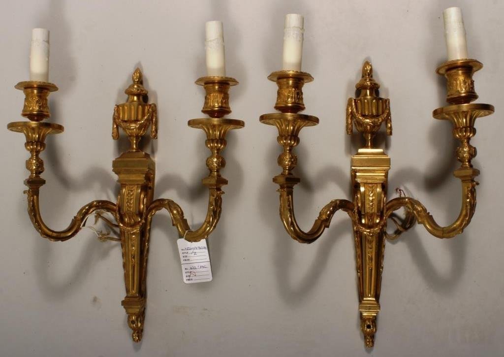 Pair of Bronze Neoclassical 2-Light Sconces: Pair of 2-light gilt bronze sconces with urn, flame and oak leaf garlands. (2 pcs.)(NSHAW8028) Measurements: Each: 14" x 5" x 17 1/2" Condition: Good Property Title: Property from a Michel Simon Inter