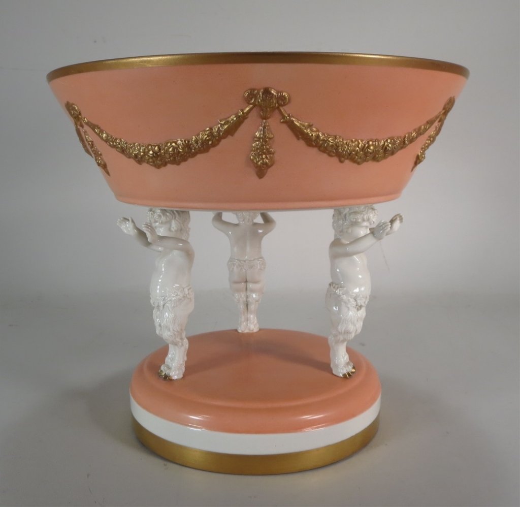 Porcelain Compote with Satyr Putti: Porcelain compote supported by 3 satyr putti. Pale salmon and gilt(NSHAW8031) Measurements: 10" H x 11 1/2" Dia. Condition: Good Property Title: Property from a Michel Simon Interiors Designed Collect