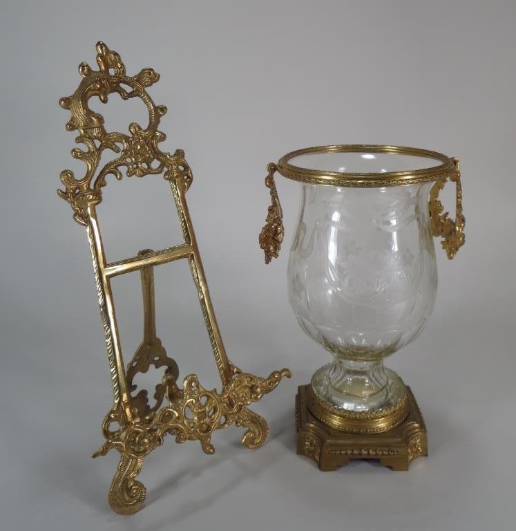 French Ormolu Vase & Easel: French Ormolu Vase & Easel, the cut glass vase with etched decoration. The easel of table top variety (2 Pieces)(NSHA8026) Low Estimate: 200 High Estimate: 300 Measurements: Vase 11"H x 5" DIA Easel 1