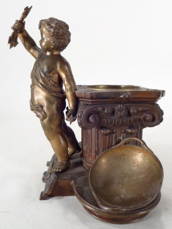 Bronze Sculpture of Eros, c.1857: A Bronze Sculpture of Eros Holding Arrows and Leaning on a Corinthian Capitol, French, 19th C, with a date of 1857; possibly an ecritoire. (29)(ELBE6922) Low Estimate: 600 High Estimate: 900 Measureme