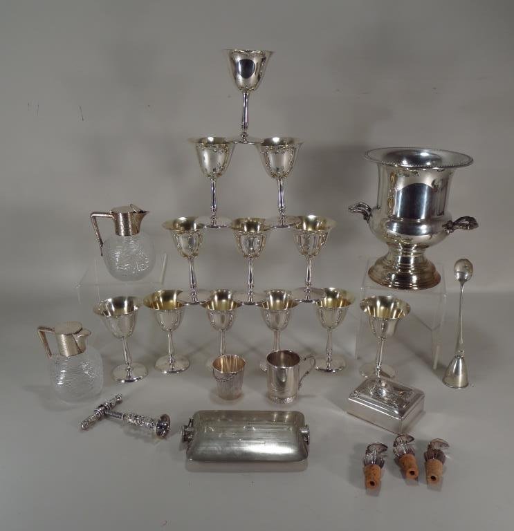 Lot Of Silver Plate Bar Ware: Lot of silver plate bar ware, includes 12 wine glasses, a wine cooler, cork pull, two covered jugs, a jigger, cigarette box, flask, etc.(GREE2300/LOT) {PR} Measurements: Various Sizes Condition: Light