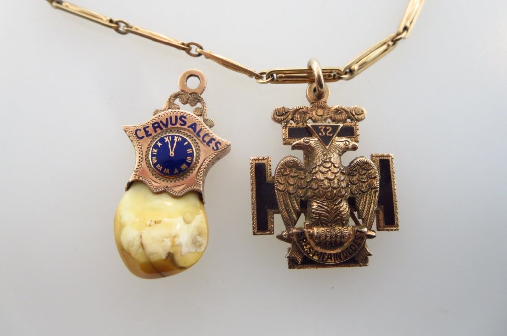 10k Victorian Fraternal Pendants on 10k Chain: One Elks pendant with enameled clock and elks tooth "New Castle. C. E. Leslie. No. 69" inscribed. The other bears a two headed eagle, the # 32 and a Latin inscription "Spes Meain Deo Est" indicating S
