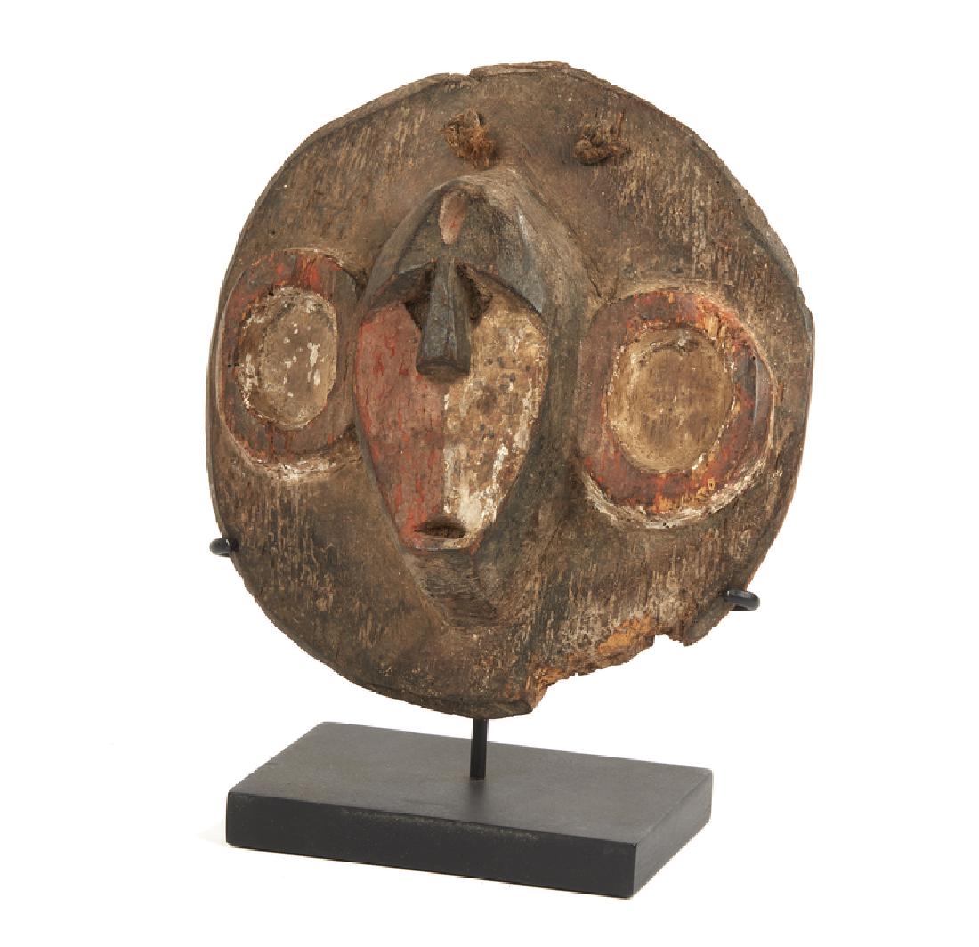 Boa Monkey-Form Mask: Boa (Democratic Republic of Congo) polychrome face in the form of a monkey carved on round wood board. Mounted on custom stand. Dimensions: 8". Provenance: The estate of Jean-Pierre Hallet. Processing