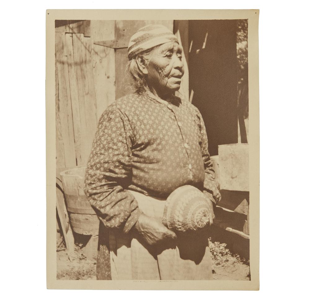 Grace Nicholson Photograph of Karok Indian Woman: Photograph of Karok Indian woman by Grace Nicholson. Handwritten in ink description verso. Stamped, verso, "Photo by Grace Nicholson, Pasadena, Cal." Dimensions: (overall) 11.37"h x 8.87"w. Processing